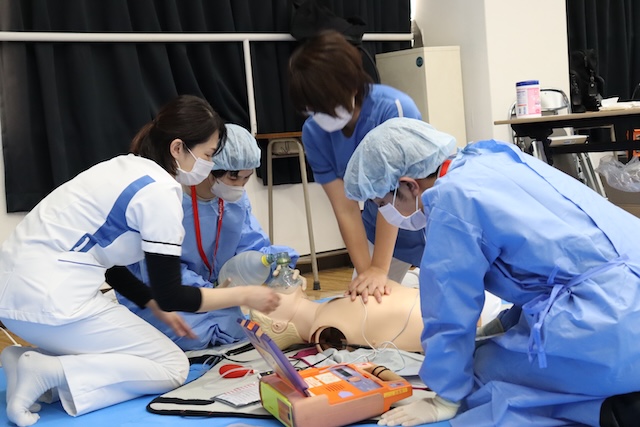 胸骨圧迫の方法を教えられる参加者たち（洛和会音羽病院ご提供）